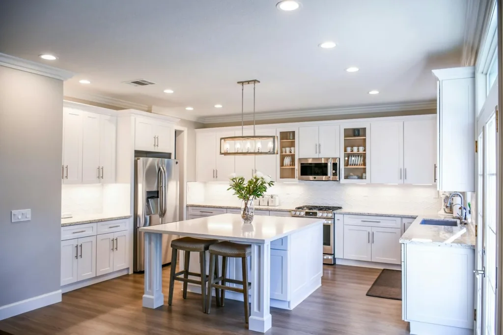 Bright remodeled kitchen with white cabinets and granite island